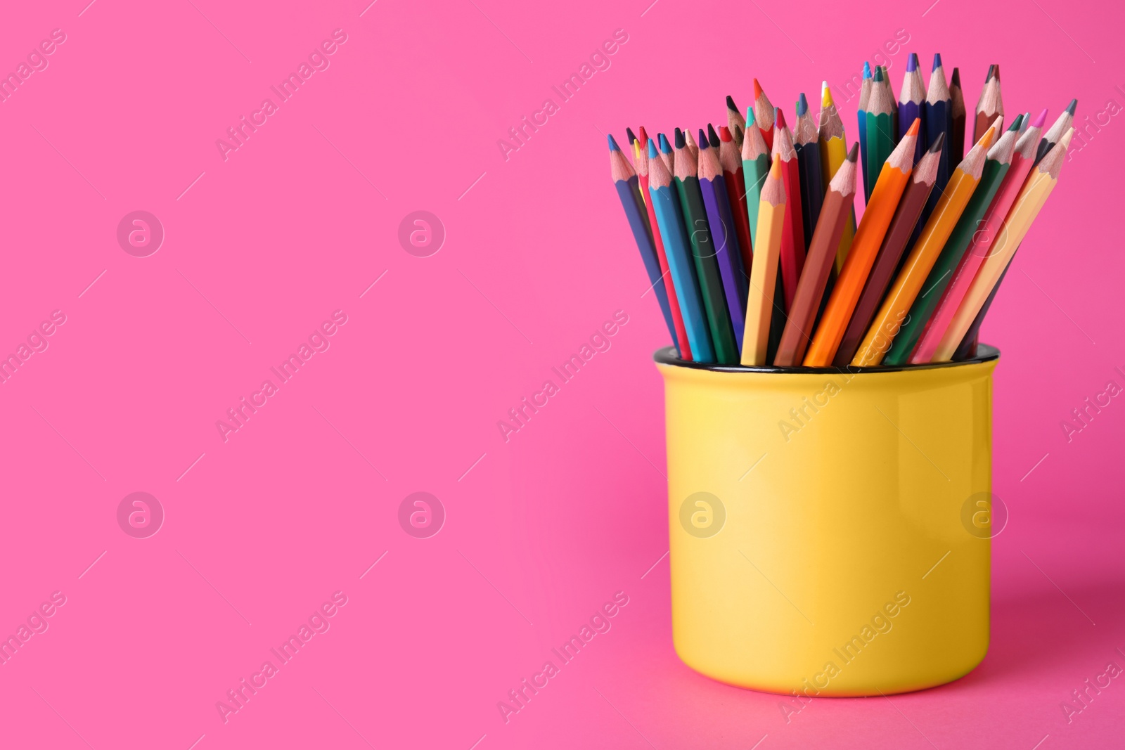 Photo of Colorful pencils in mug on pink background. Space for text