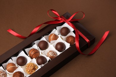 Box with delicious chocolate candies on brown table, closeup