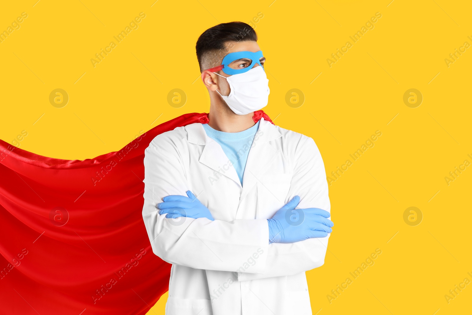 Photo of Doctor wearing face mask and cape on yellow background. Super hero power for medicine