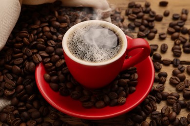 Image of Cup of aromatic hot coffee and beans on wooden table