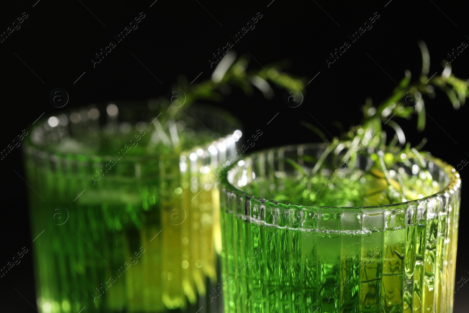 Photo of Glasses of homemade refreshing tarragon drink on black background, closeup