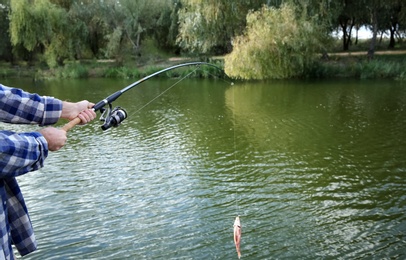 Man with rod fishing at riverside, closeup. Recreational activity