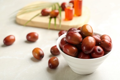 Palm oil fruits in bowl on white table, closeup