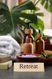 Photo of Card with word Retreat and different spa products on grey table
