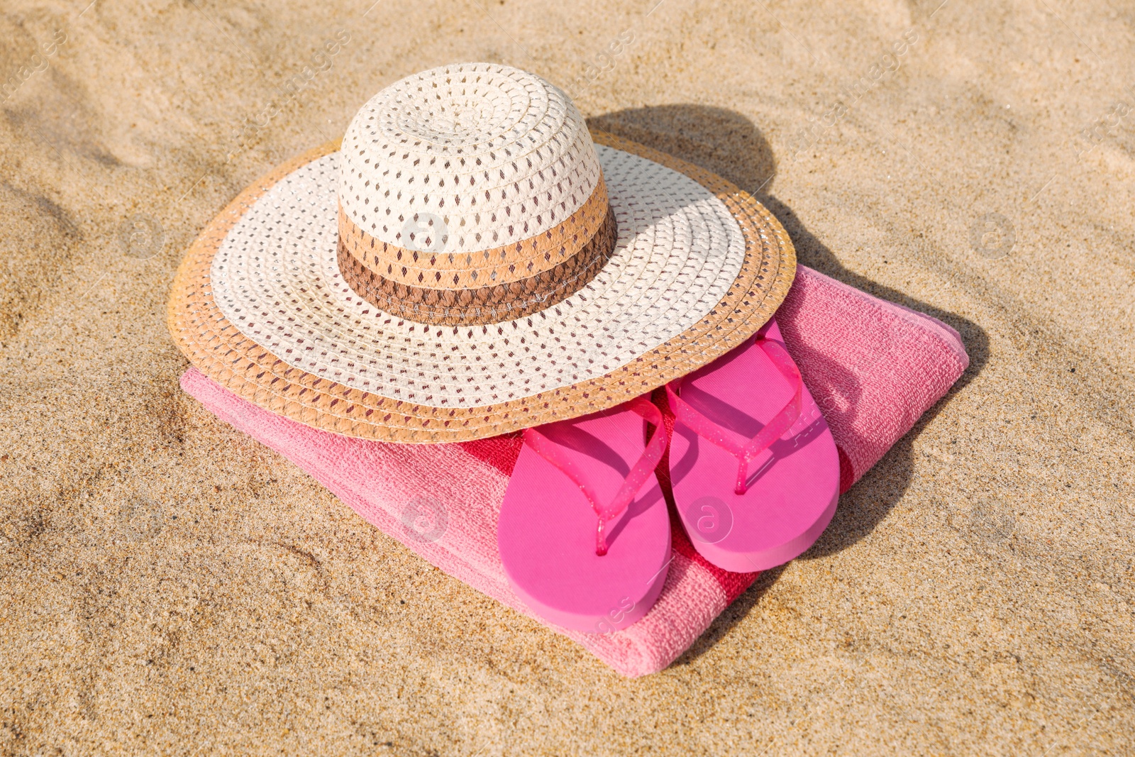 Photo of Beach towel with straw hat and slippers on sand