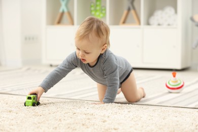 Photo of Children toys. Cute little boy playing with toy car on rug at home