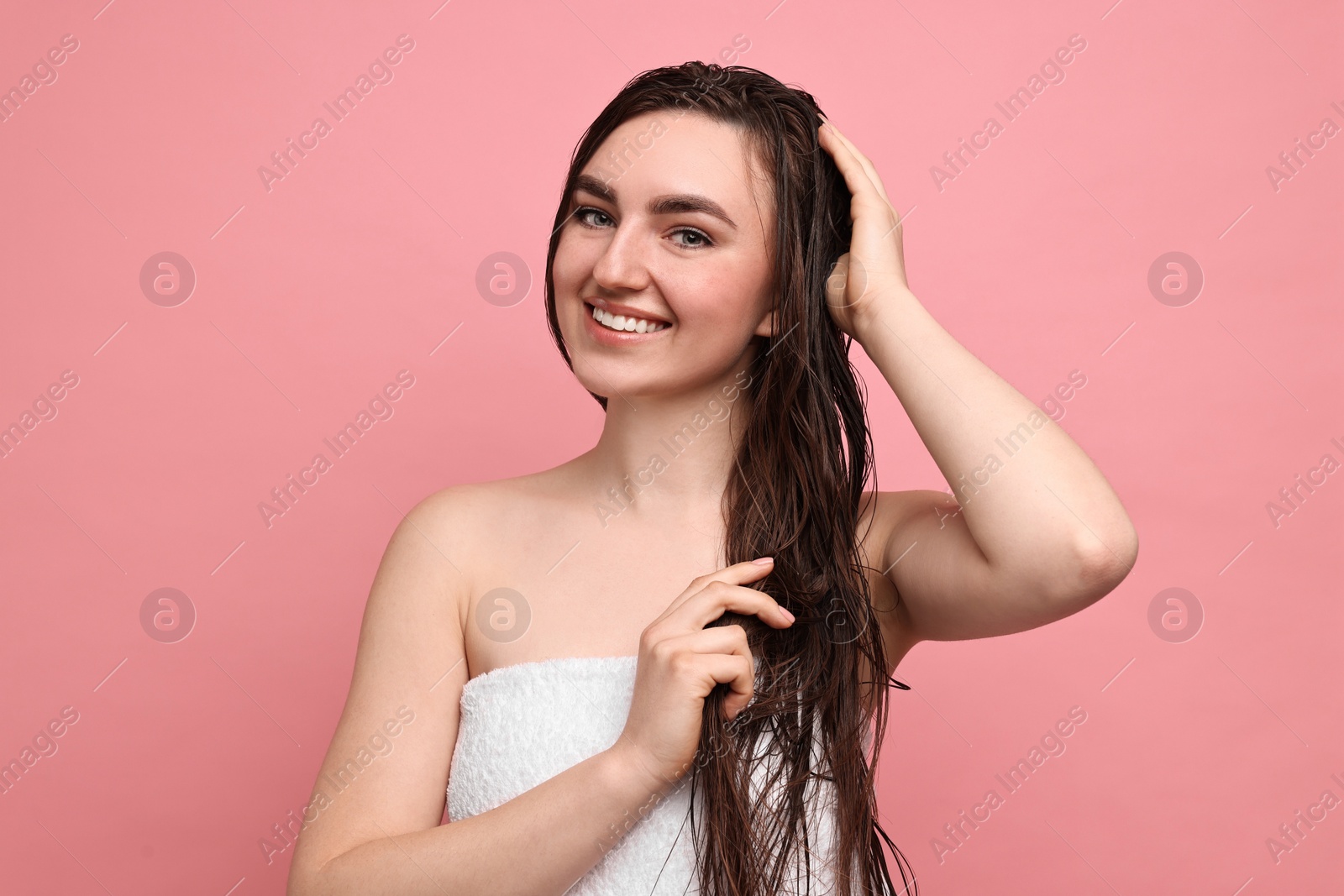 Photo of Young woman applying hair mask on pink background