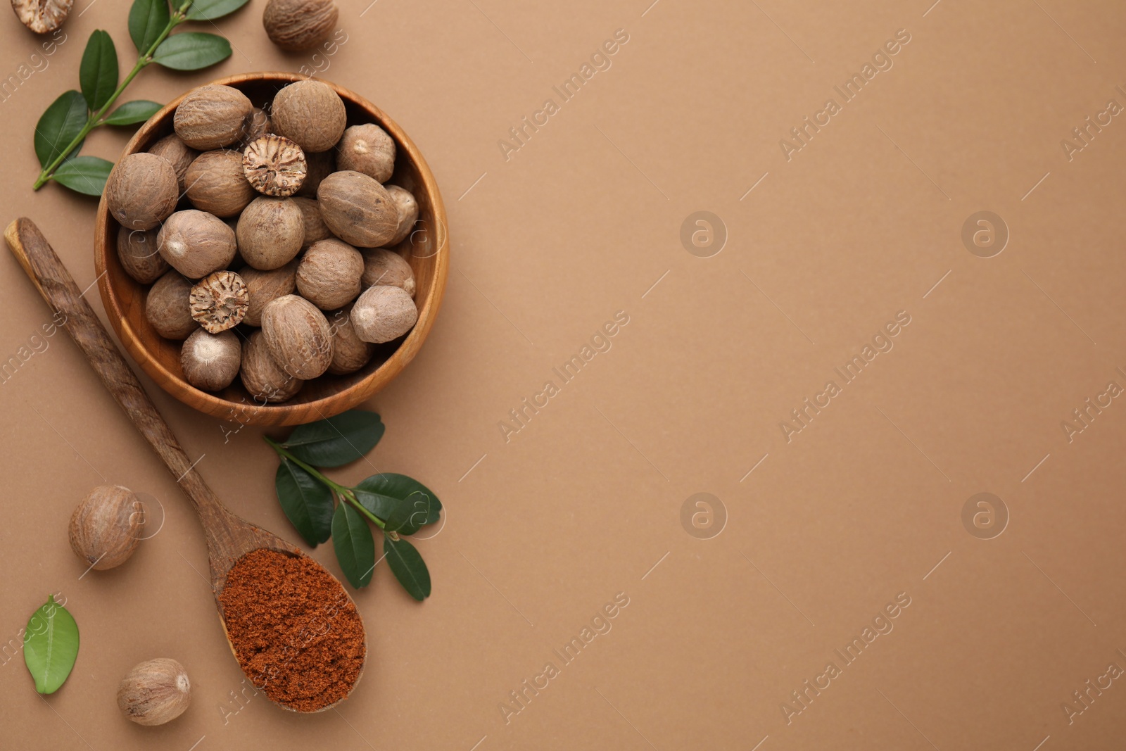 Photo of Flat lay composition with nutmegs on light brown background. Space for text