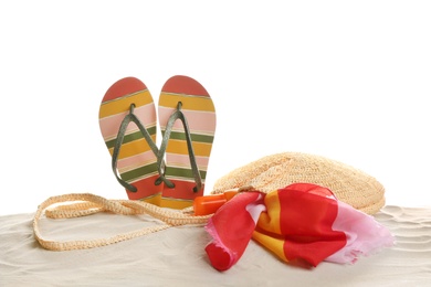 Different beach accessories on sand against white background