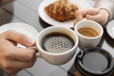 Friends drinking coffee at wooden table in outdoor cafe, closeup