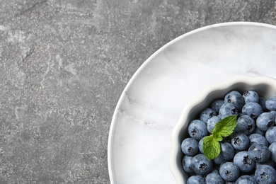 Photo of Crockery with juicy blueberries and space for text on color table, top view