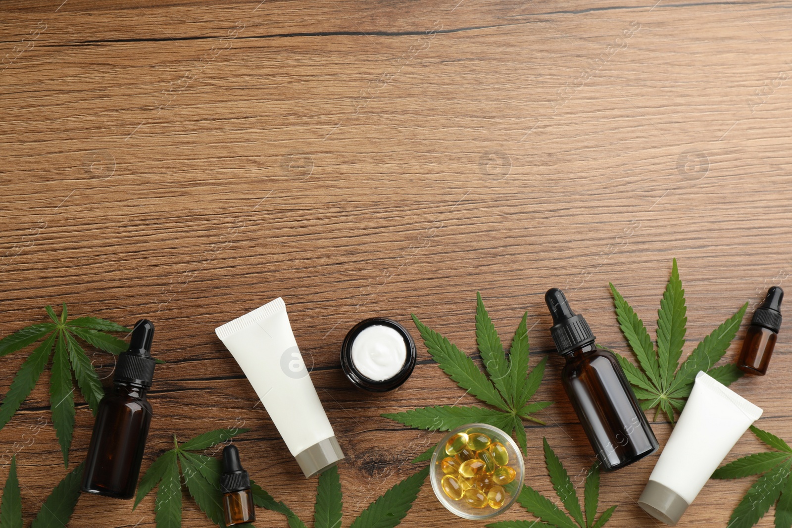 Photo of Composition with CBD oil, THC tincture and hemp leaves on wooden table, flat lay. Space for text