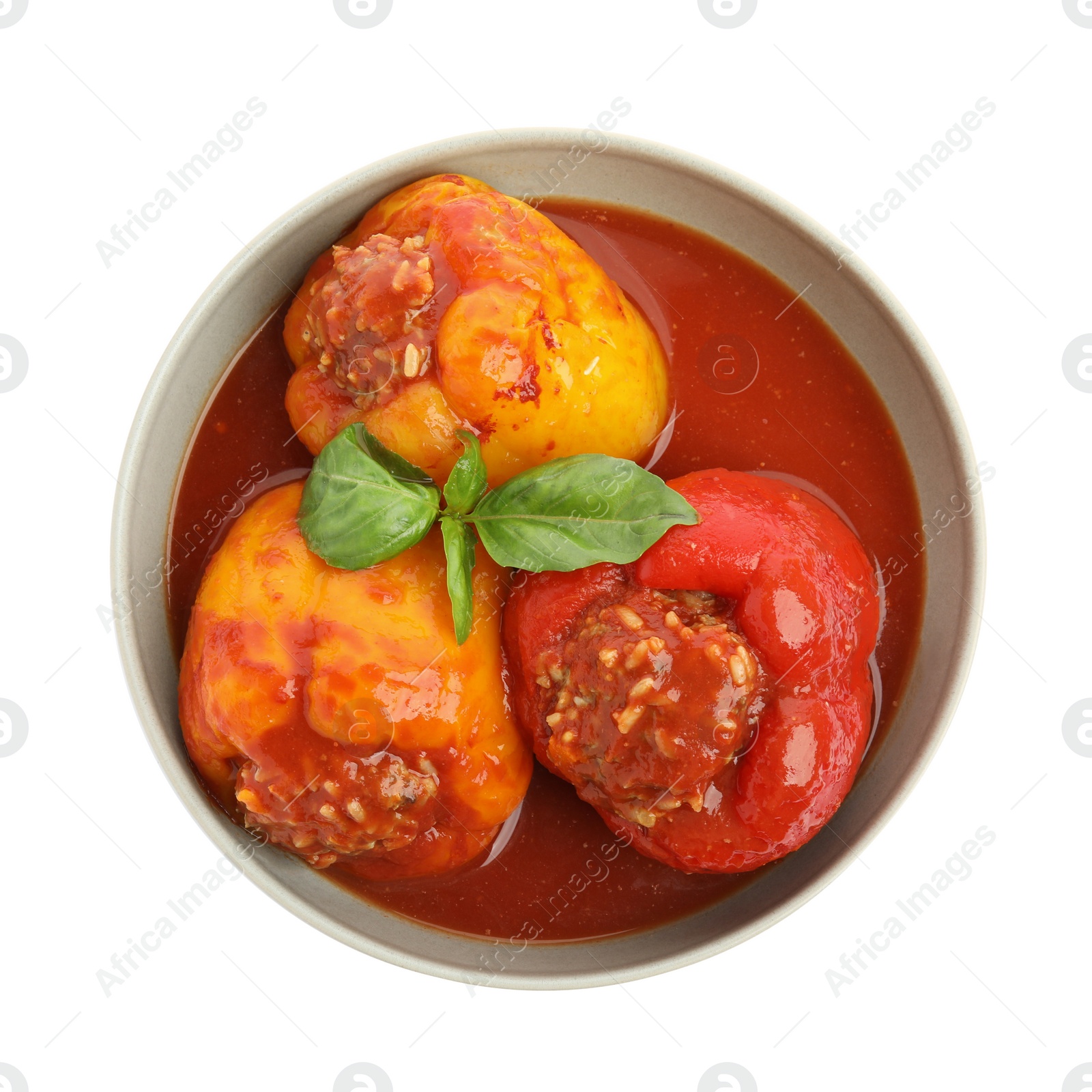 Photo of Delicious stuffed peppers with basil in bowl isolated on white, top view