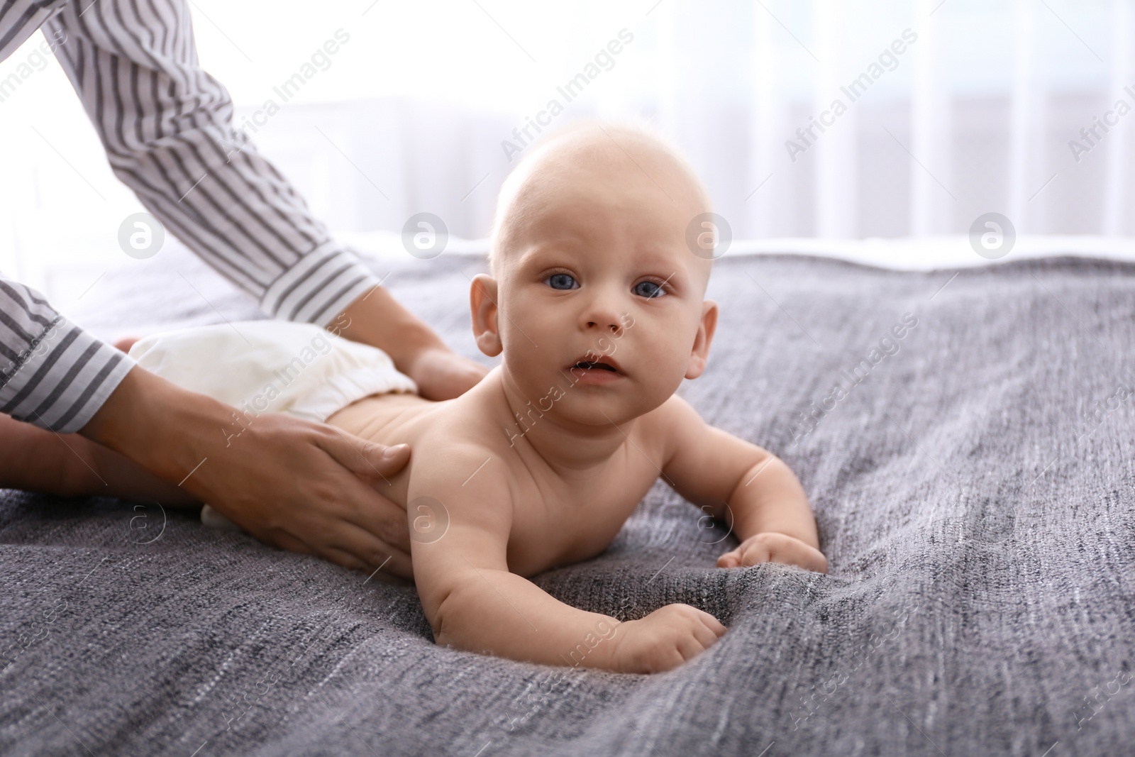 Photo of Young woman massaging cute little baby on bed at home