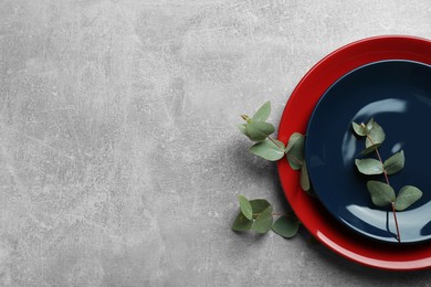 Photo of Beautiful plates with green leaves on grey table, top view. Space for text