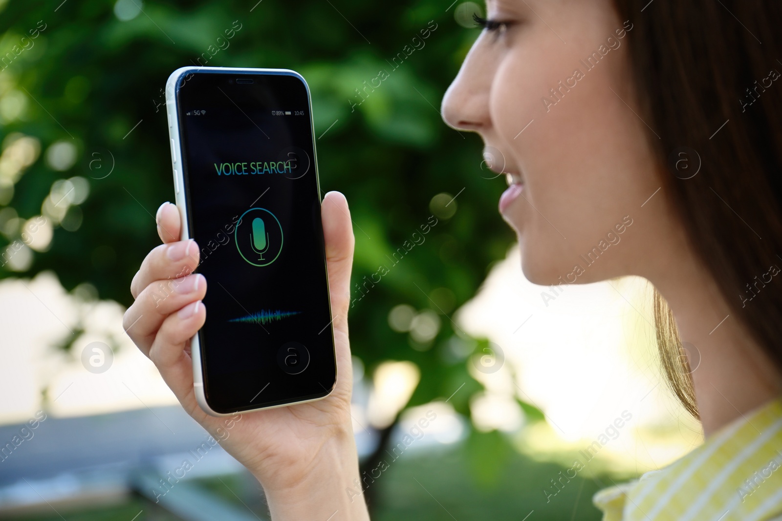 Photo of Woman using voice search on smartphone outdoors, closeup