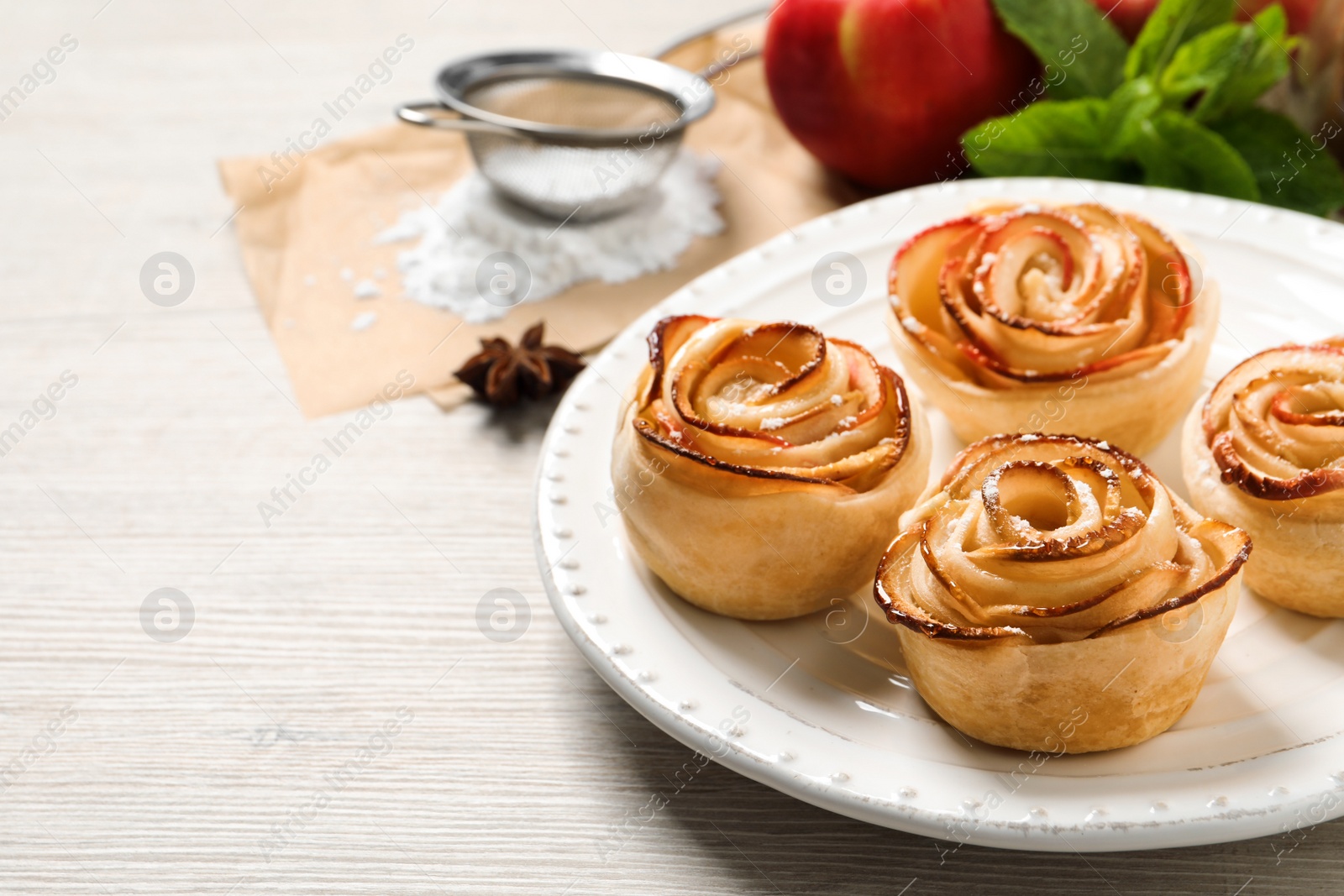 Photo of Freshly baked apple roses on white wooden table, space for text. Beautiful dessert