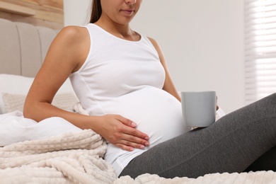 Pregnant woman drinking tea at home, closeup