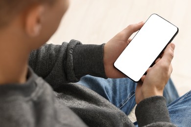 Photo of Man using smartphone with blank screen indoors, closeup. Mockup for design