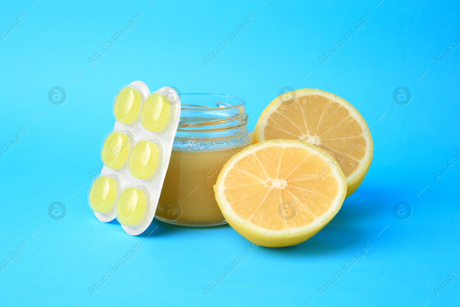 Photo of Blister with cough drops, fresh lemon and honey on light blue background