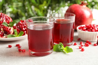 Composition with glasses of fresh pomegranate juice on table