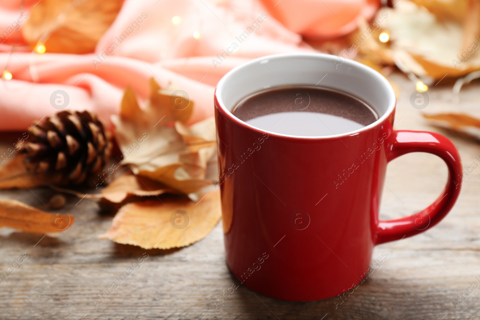 Photo of Cup of hot drink and leaves on wooden table. Cozy autumn atmosphere