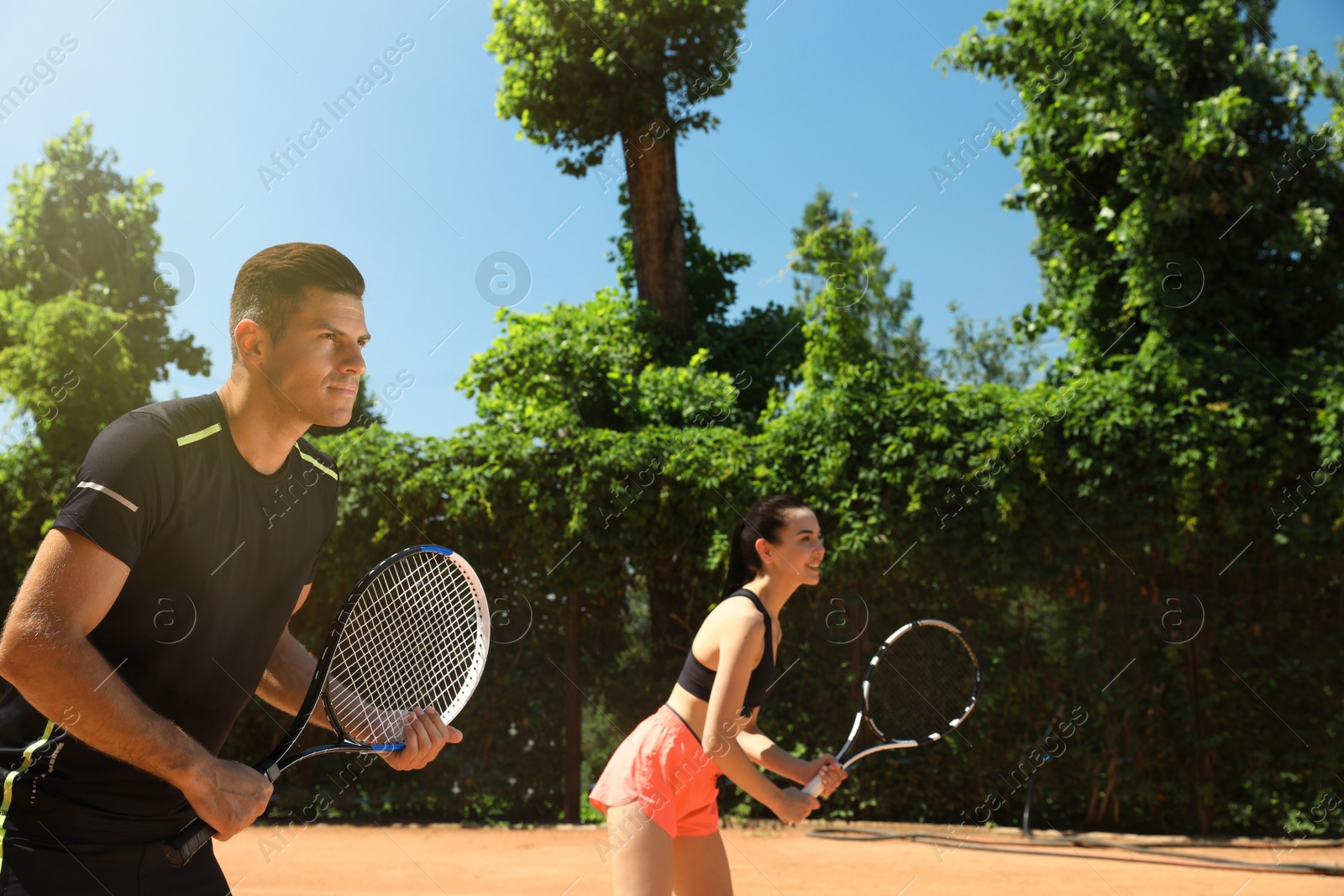 Photo of Couple playing tennis on court during sunny day