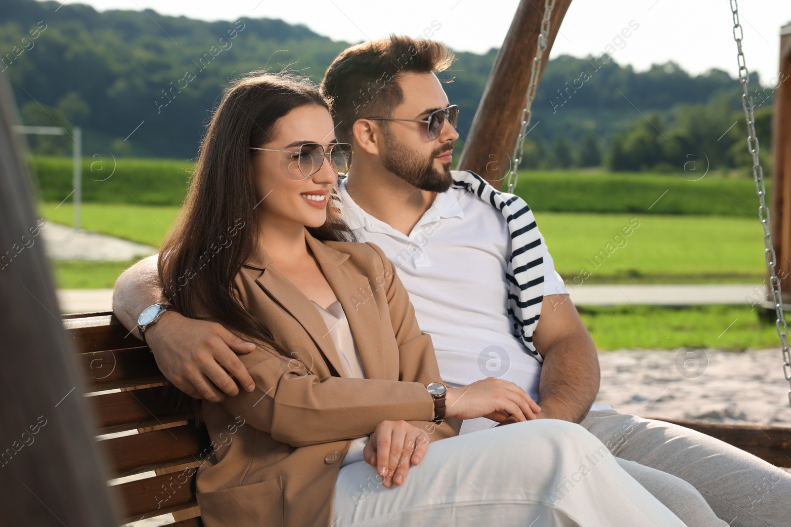 Photo of Romantic date. Beautiful couple spending time together on swing bench outdoors