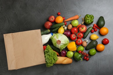 Photo of Flat lay composition with overturned paper bag and groceries on grey table