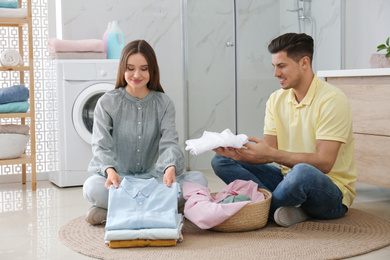 Photo of Happy couple with clean laundry in bathroom