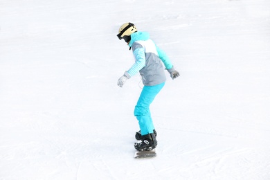 Photo of Woman in suit snowboarding on hill. Winter vacation