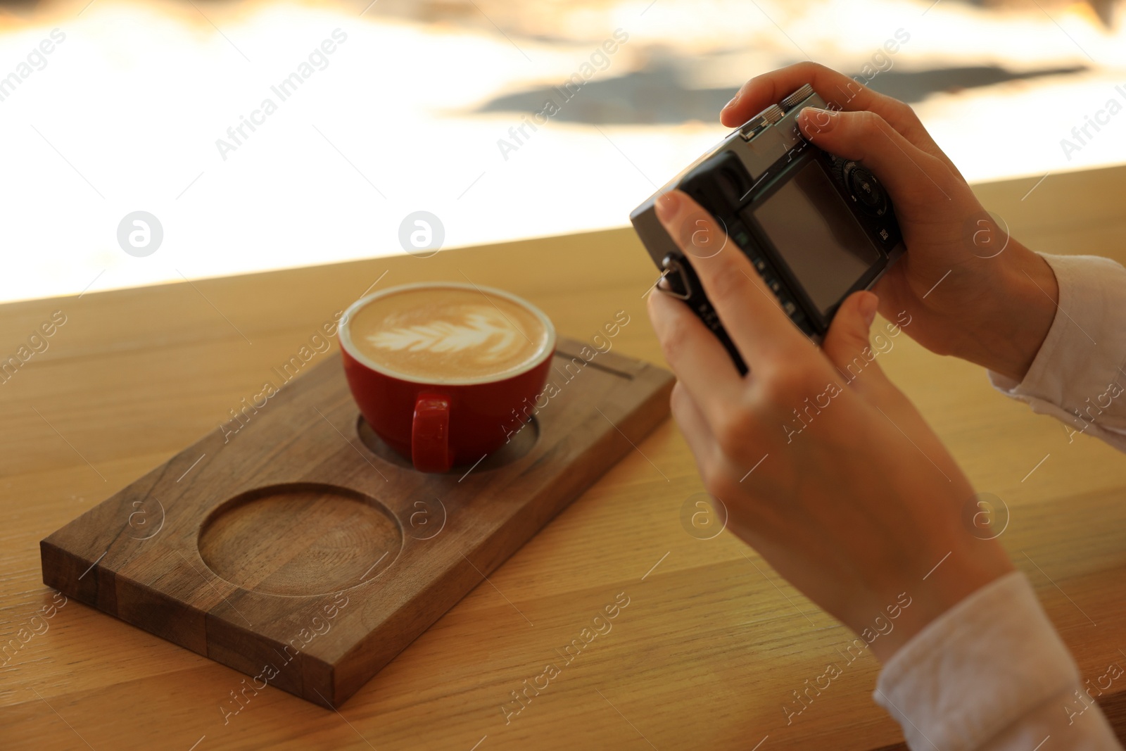 Photo of Woman taking photo of cup with coffee indoors, closeup. Creative hobby