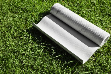 Karemat or fitness mat on green grass outdoors, space for text