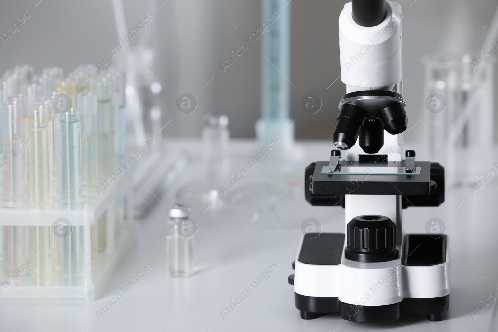 Photo of Modern medical microscope on white table in laboratory, closeup. Space for text