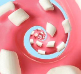 Twisted donut with strawberry icing and marshmallows on light blue background, spiral effect