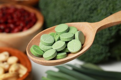 Photo of Wooden spoon of pills over foodstuff, closeup. Prebiotic supplements