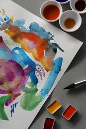 Photo of Abstract watercolor painting, colorful paints and brush on grey table, flat lay