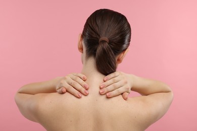 Photo of Woman touching her neck on pink background, back view