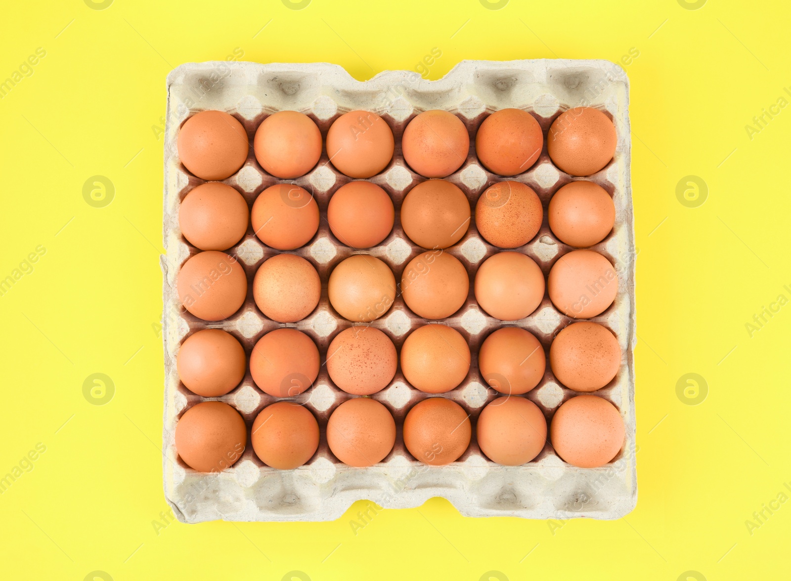 Photo of Raw chicken eggs on yellow background, top view