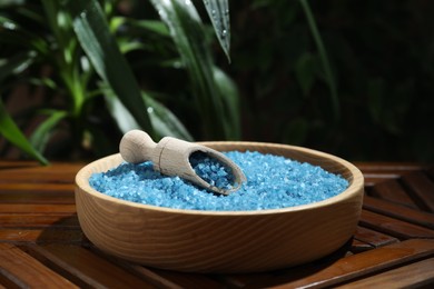 Bowl of blue sea salt with scoop on wooden table