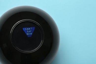 Photo of Magic eight ball with prediction Can't Say Now on light blue background, top view. Space for text