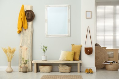 Photo of Hallway interior with wooden bench, clothes and mirror