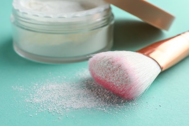 Photo of Rice loose face powder and makeup brush on turquoise background, closeup