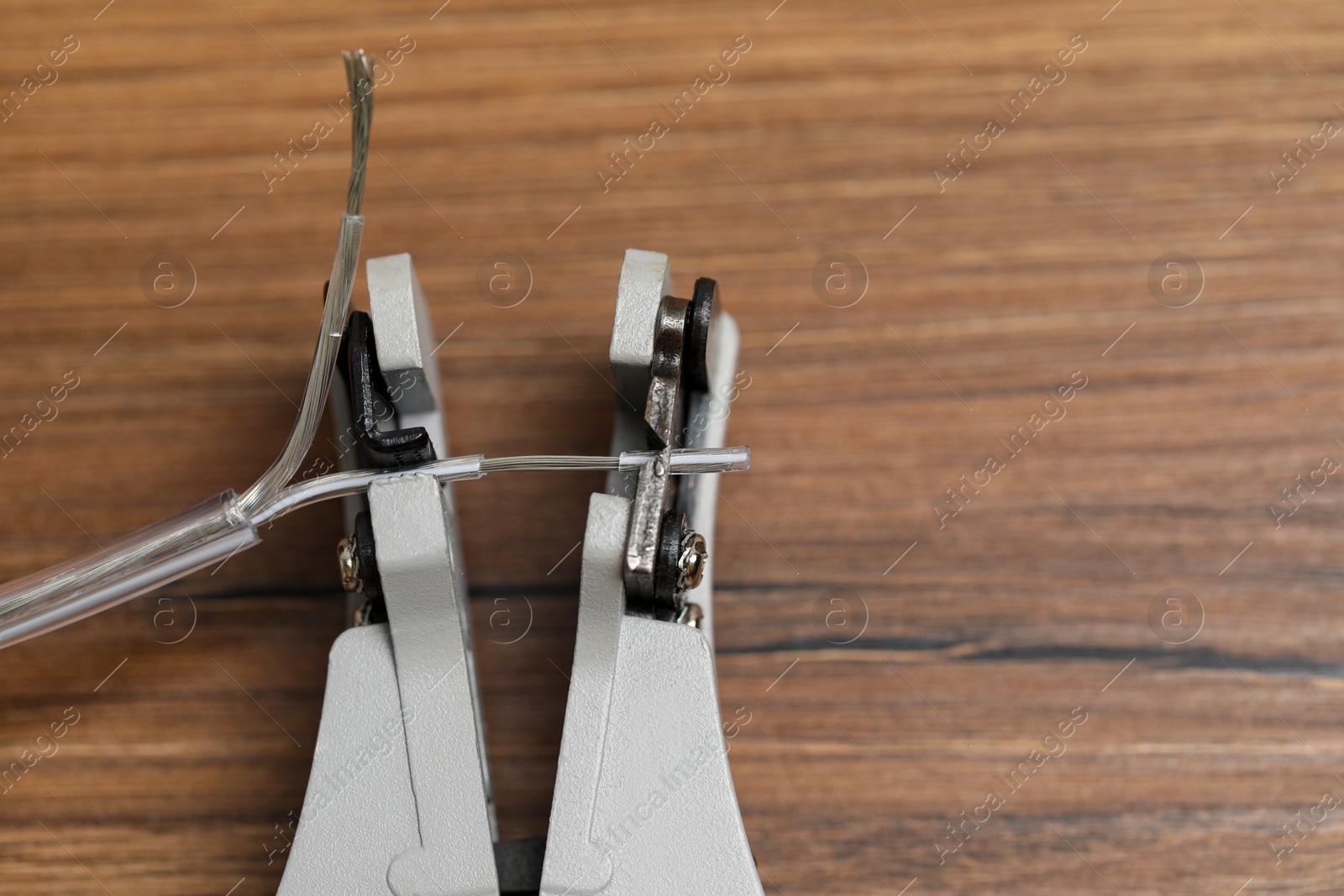 Photo of Cutters and stripped wire on wooden table, closeup. Space for text