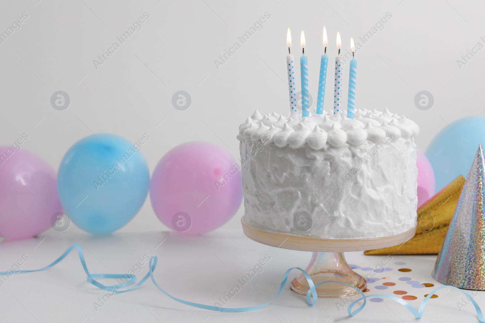 Photo of Delicious cake with burning candles and decorations on white table. Space for text