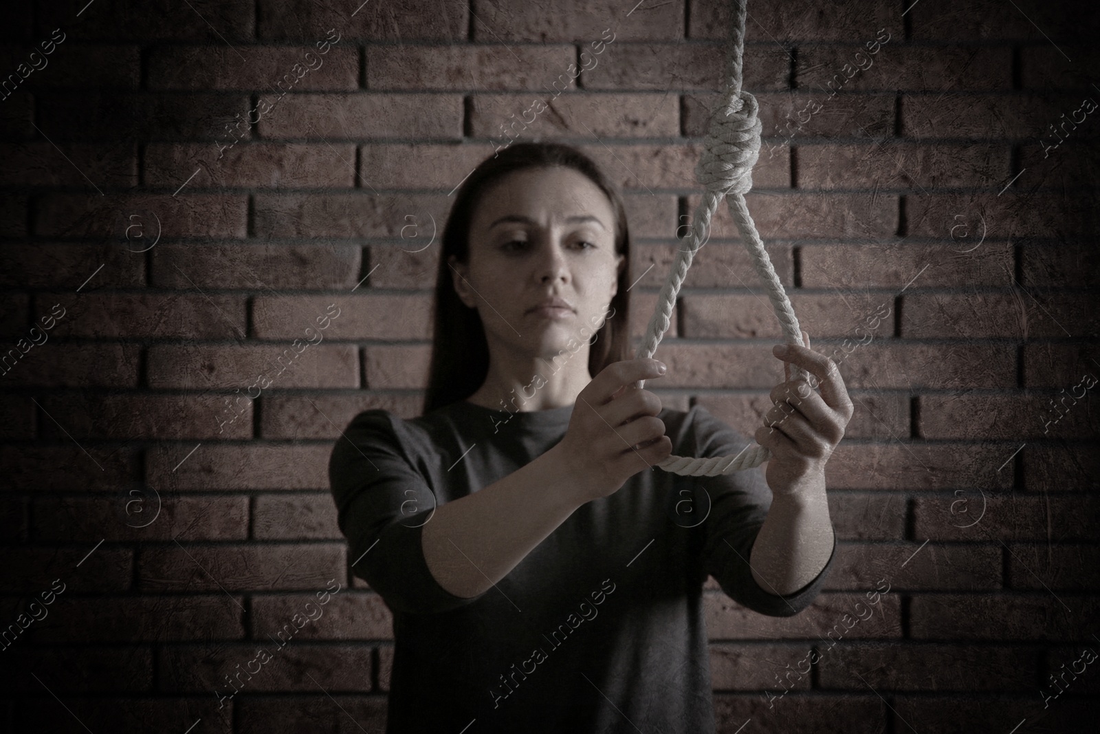 Image of Depressed woman with rope noose near brick wall. Suicide concept