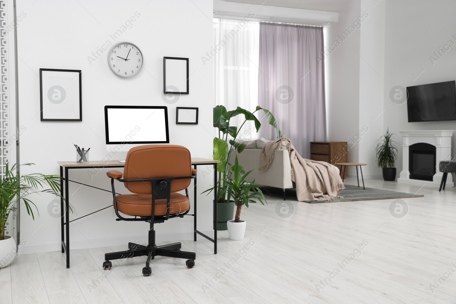 Photo of Stylish room interior with comfortable office chair, desk and houseplants