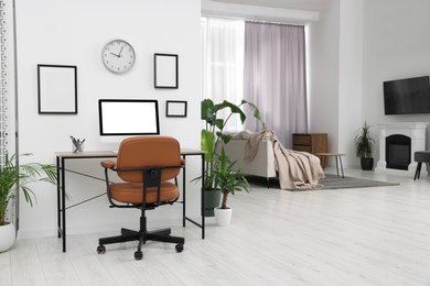 Stylish room interior with comfortable office chair, desk and houseplants