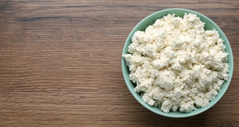Photo of Delicious fresh cottage cheese on wooden table, top view. Space for text