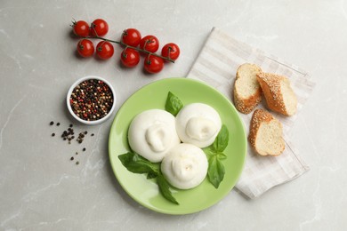 Photo of Delicious burrata cheese with basil served on light table, flat lay